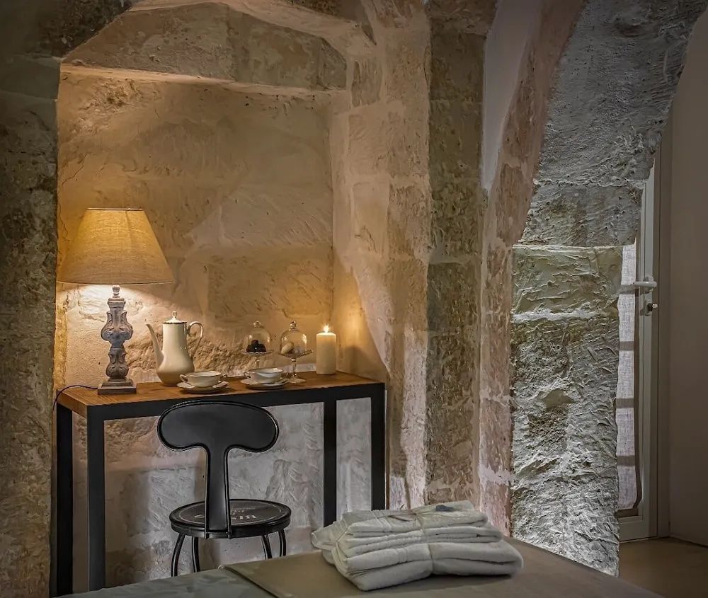Holzschreibtisch mit Tischlampe in einer Nische mit historischen Gewölbewänden aus Stein.