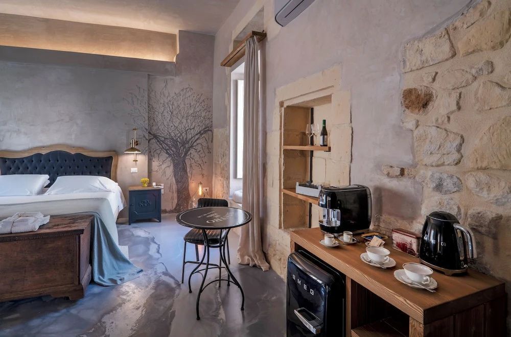 Sitzbereich im Zimmer mit kleinem Tisch, Stuhl und einer Kaffeestation auf der Kommode.