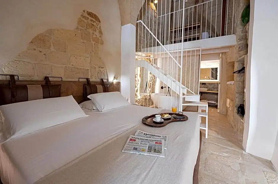 Hotelzimmer mit freigelegtem Mauerwerk, Doppelbett und einer Treppe zur Empore.