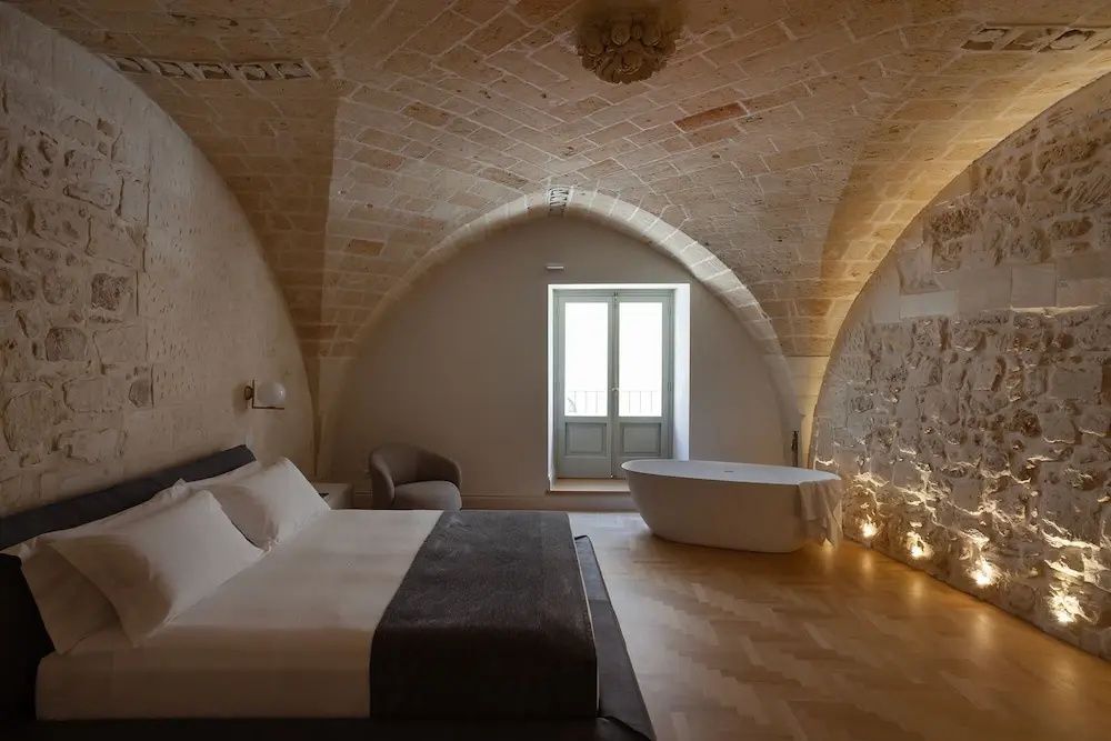 Geräumiges Schlafzimmer unter einem Gewölbe aus Stein mit Doppelbett und Wanne.