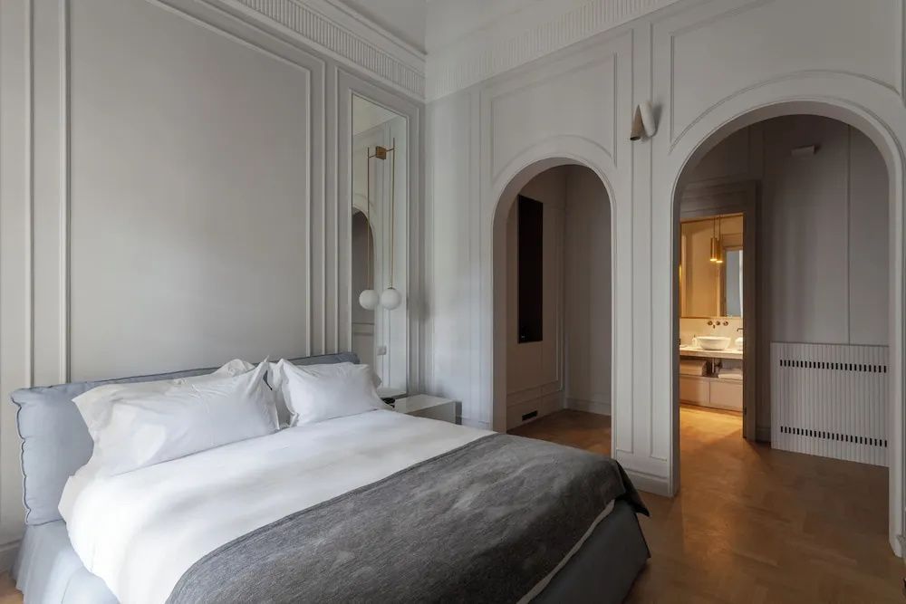 Hotelzimmer mit Doppelbett, Wandverzierungen und Rundbögen zum Badbereich.