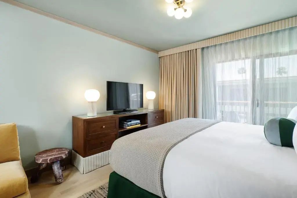 Zimmerbereich mit hölzernem Sideboard, Fernseher und Vorhang am Fenster.