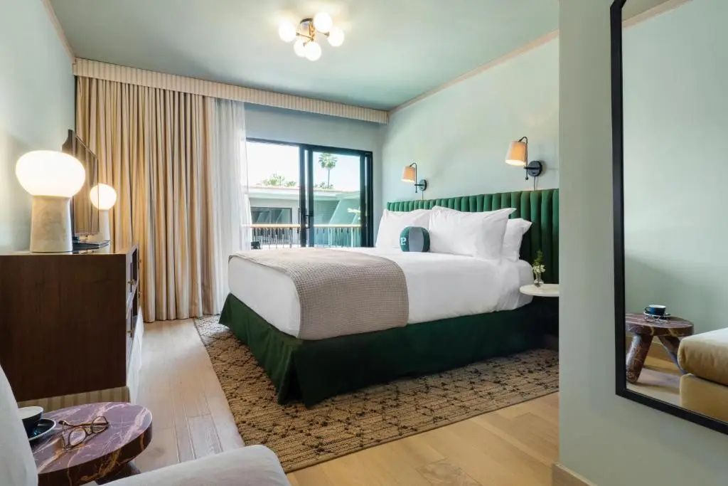 Hotelzimmer mit großem Doppelbett, Parkettboden und Fensterschiebetür.