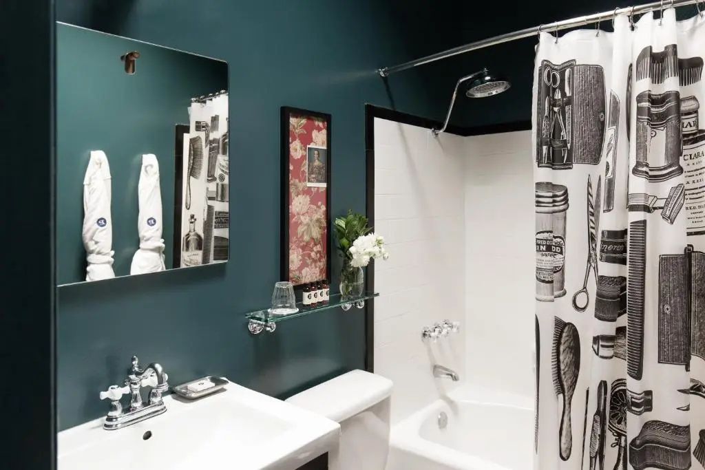 Badezimmer mit dunkelgrünen Wänden, Badewanne mit Duschvorhang und Waschtisch.