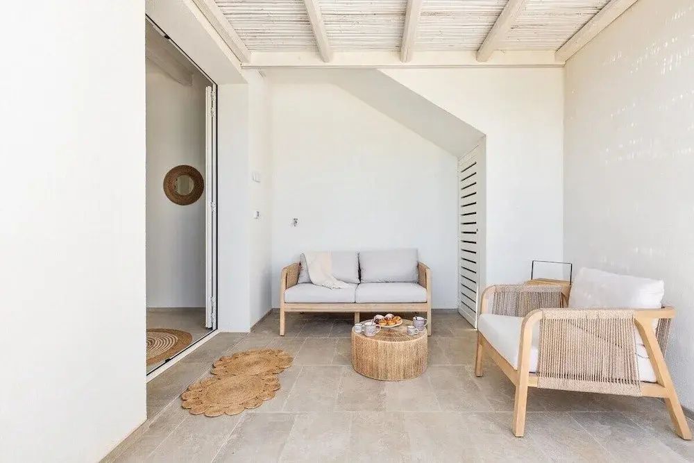 Sitzecke mit Sofa und Sesseln auf einer hellen überdachten Terrasse.