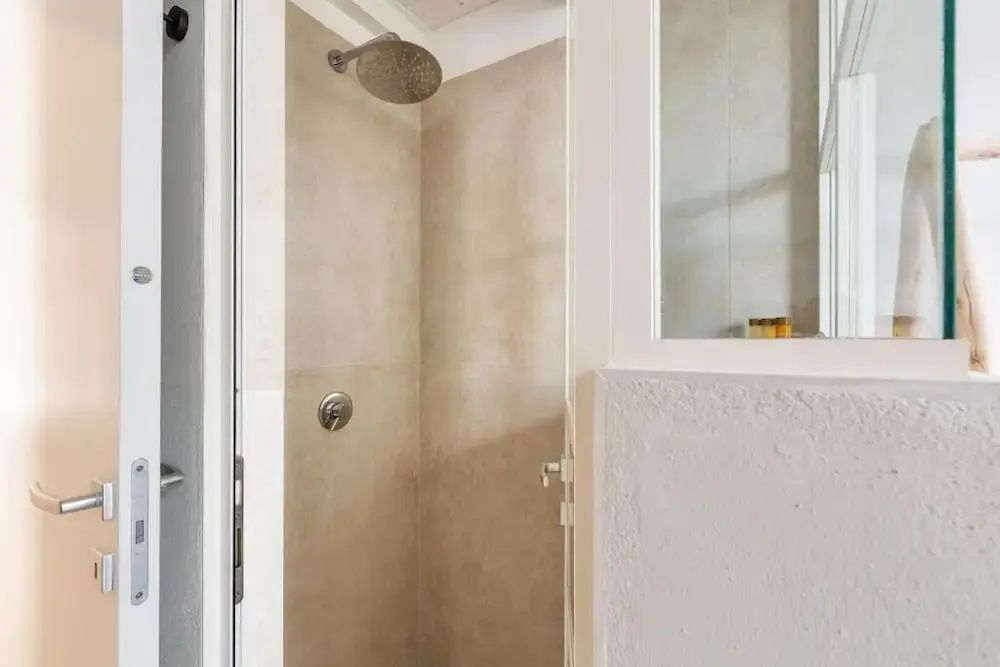 Bodengleiche Dusche mit großem Regenduschkopf und beigefarbenen Wänden.