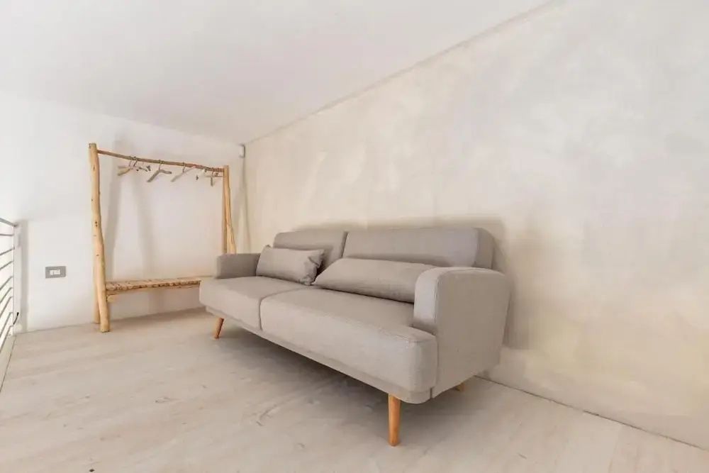 Helles Sofa mit Holzfüßen in schlicht gestaltetem Wohnbereich