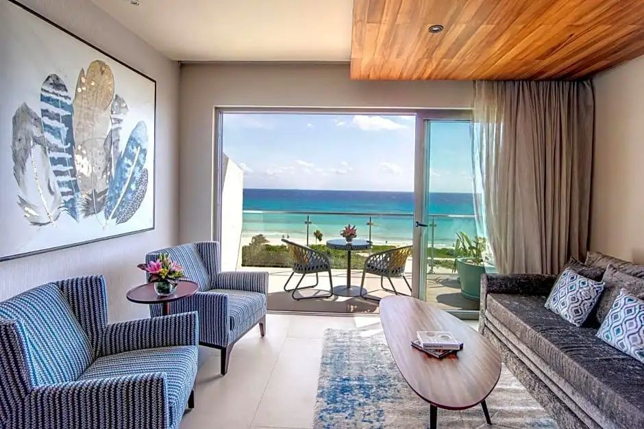 Sitzbereich einer Suite mit Sesseln und Blick auf den Balkon sowie das Meer.