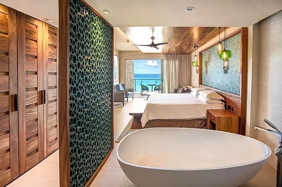 Geräumiges Schlafzimmer mit freistehender Wanne, Bett und Blick zum Meer.