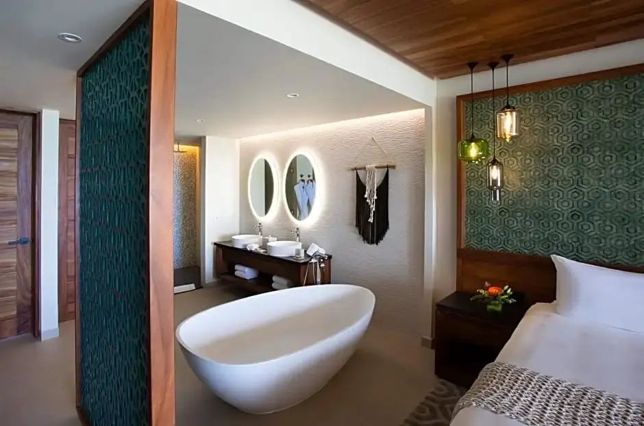 Badezimmer mit ovaler Wanne, zwei Waschbecken und beleuchteten Spiegeln.