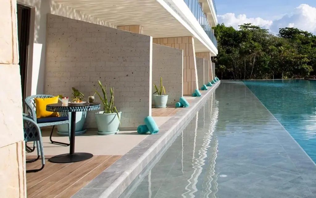 Private Terrassenbereiche an einem Swim-Up-Pool entlang der Gebäudefront.