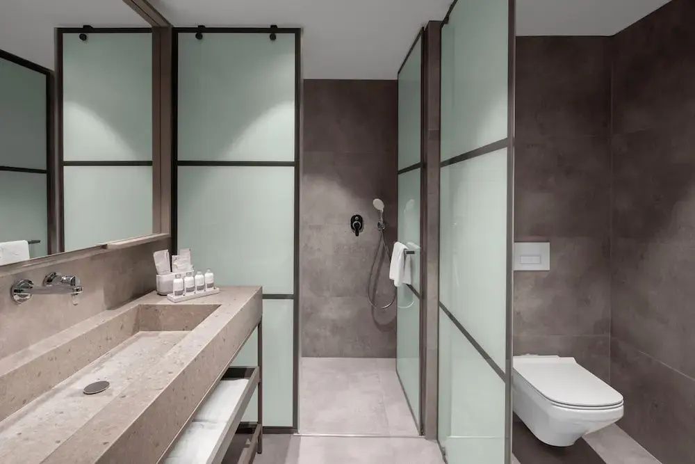 Modern eingerichtetes Badezimmer mit Waschtisch, Milchglaselementen und Dusche.