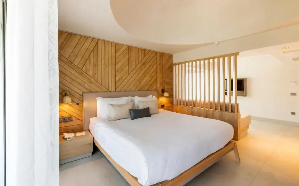 Modernes Hotelzimmer mit Doppelbett und stilvoller Wandverkleidung aus Holz.