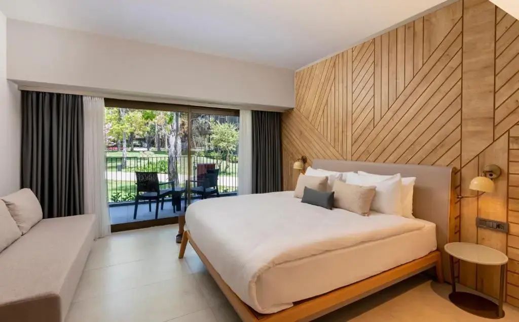 Schlafzimmer mit großem Doppelbett, Holzdekoration und Balkontür ins Grüne.