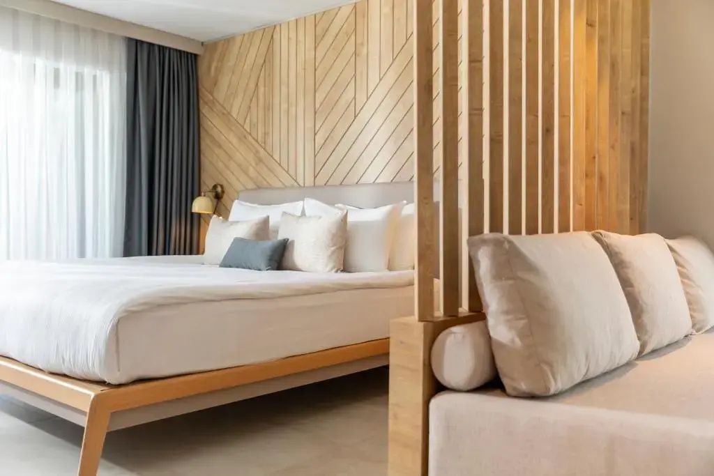 Doppelbett und Raumteiler aus Holz im modern gestalteten Hotelzimmer.