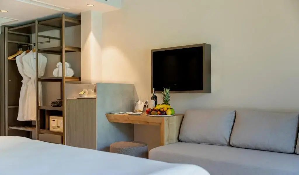 Sitzbereich im Zimmer mit bequemem Sofa, Wandfernseher und kleiner Schreibecke.