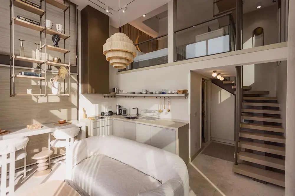 Maisonette-Zimmer mit Küchenzeile, Sofa und Empore für den Schlafbereich.