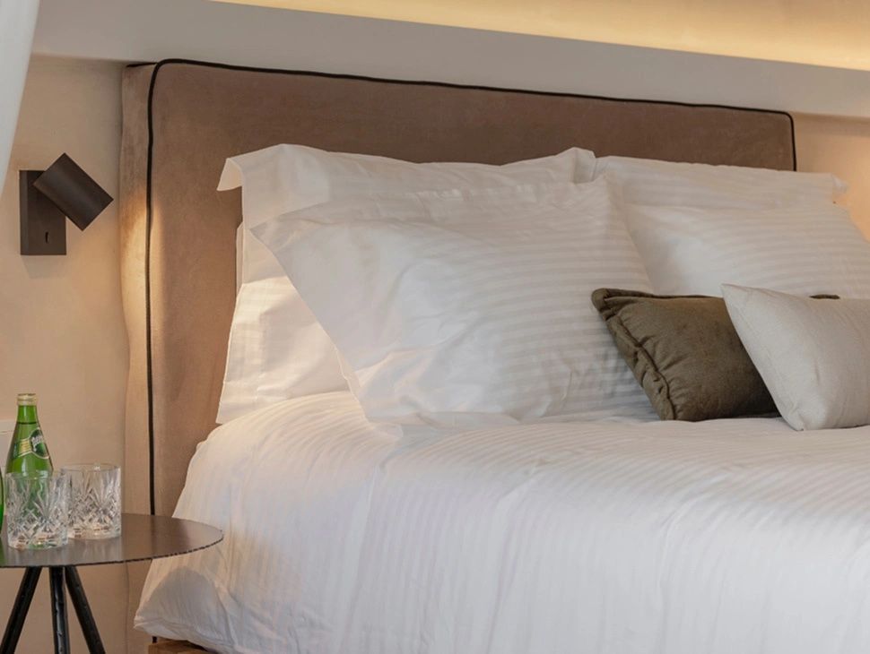 Doppelbett mit weißen Kissen und einem gepolsterten Kopfteil im Hotelzimmer.