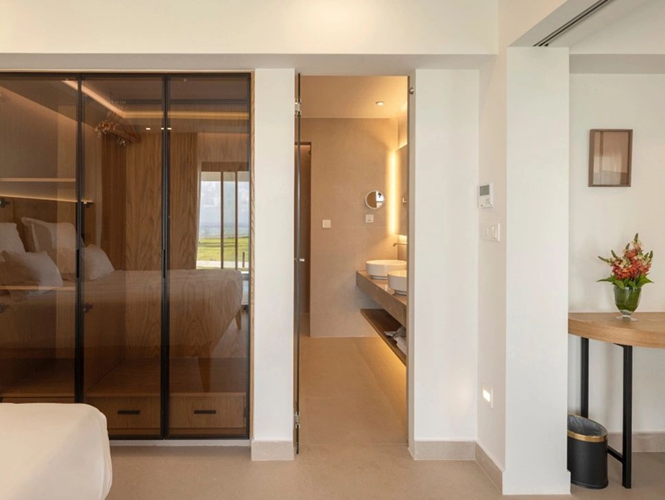 Blick in ein Zimmer mit getöntem Einbauschrank und Durchgang zum Badezimmer.