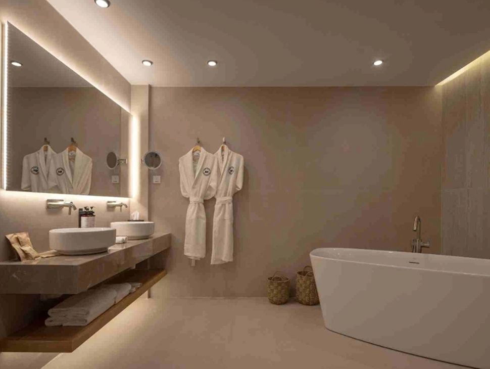 Badezimmer mit freistehender Badewanne, Doppelwaschtisch und zwei Bademänteln an der Wand.