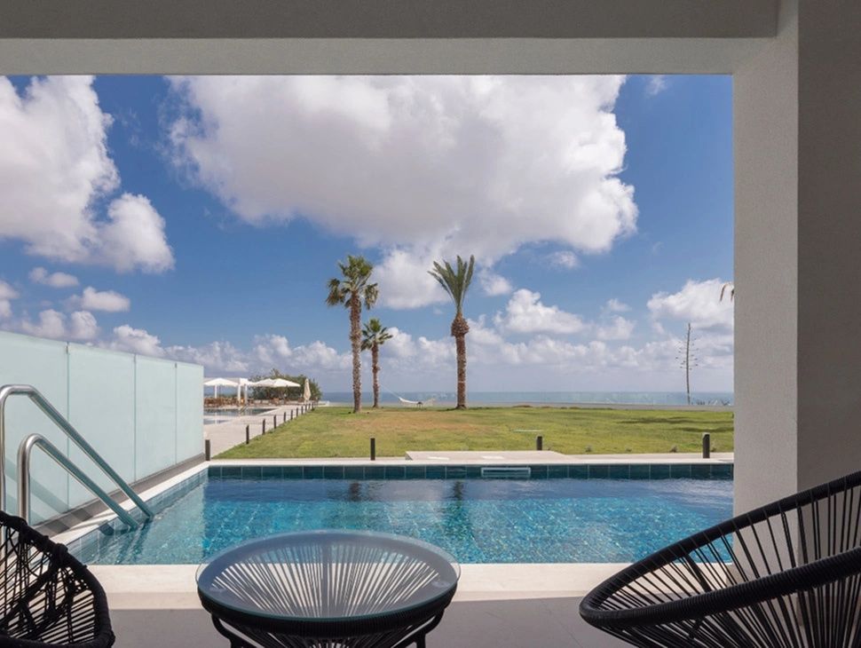 Terrasse mit privatem Pool und Blick über den Garten auf das Meer unter bewölktem Himmel.