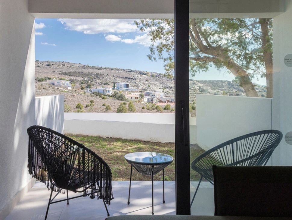Terrasse mit modernen schwarzen Sesseln und weitem Blick auf die hügelige Landschaft.