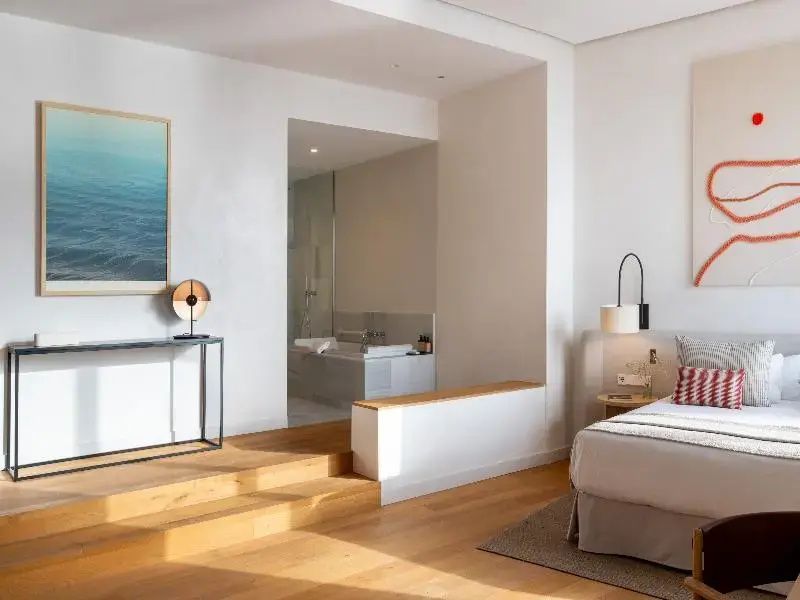 Modernes Hotelzimmer mit hellem Holzboden und Blick auf das integrierte Bad.