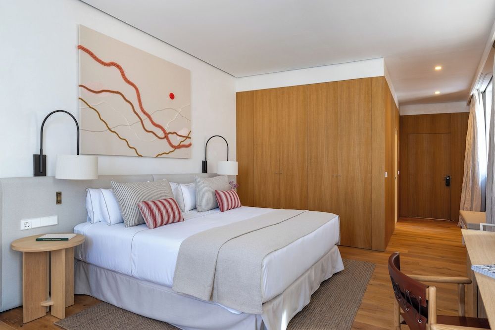 Doppelbett mit gestreiften Kissen vor Holzschrank und Kunstwerk an der Wand