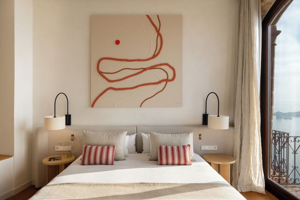 Doppelbett mit gestreiften Kissen, Wandkunst und Wandleuchten im Schlafbereich