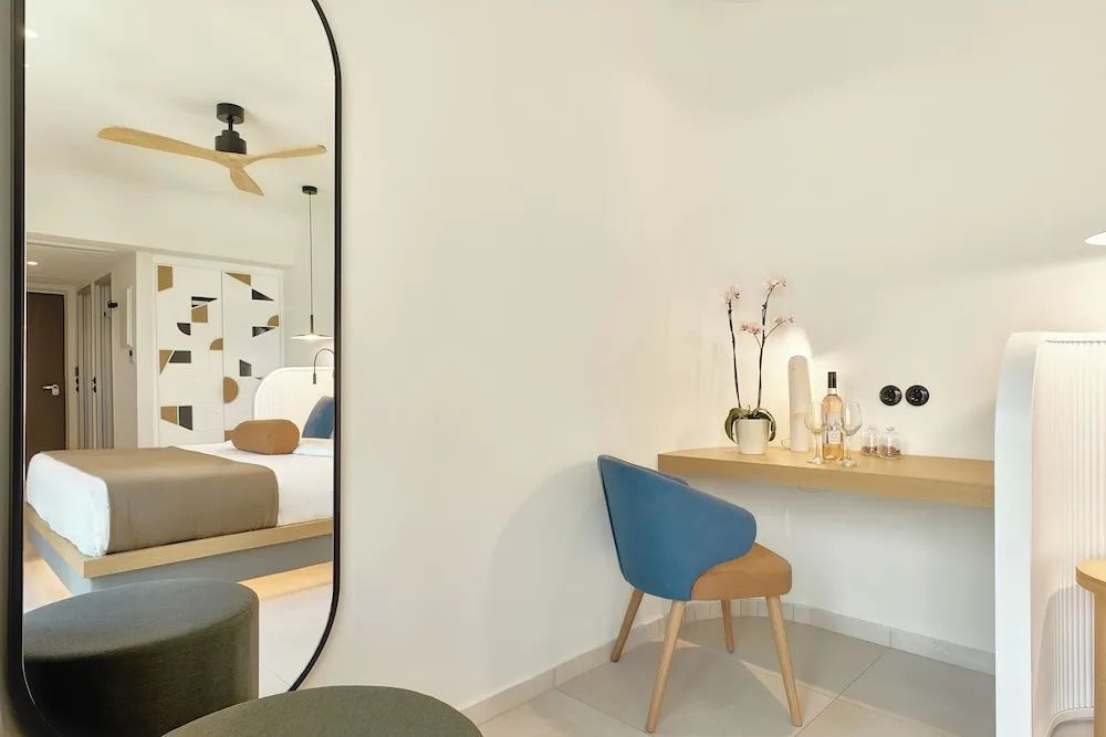 Schreibtisch mit blauem Stuhl und Dekoration neben einem großen Wandspiegel im Zimmer.