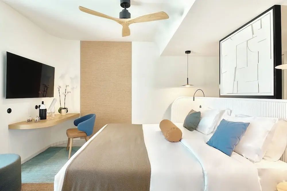 Heller Schlafraum mit einem Doppelbett, Holzventilator und Schreibtisch.
