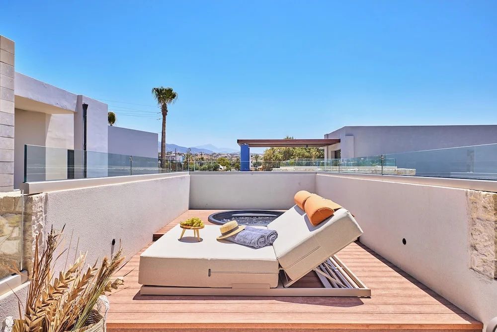 Sonnige Terrasse mit gepolsterter Doppelliege und eingebautem Whirlpool.
