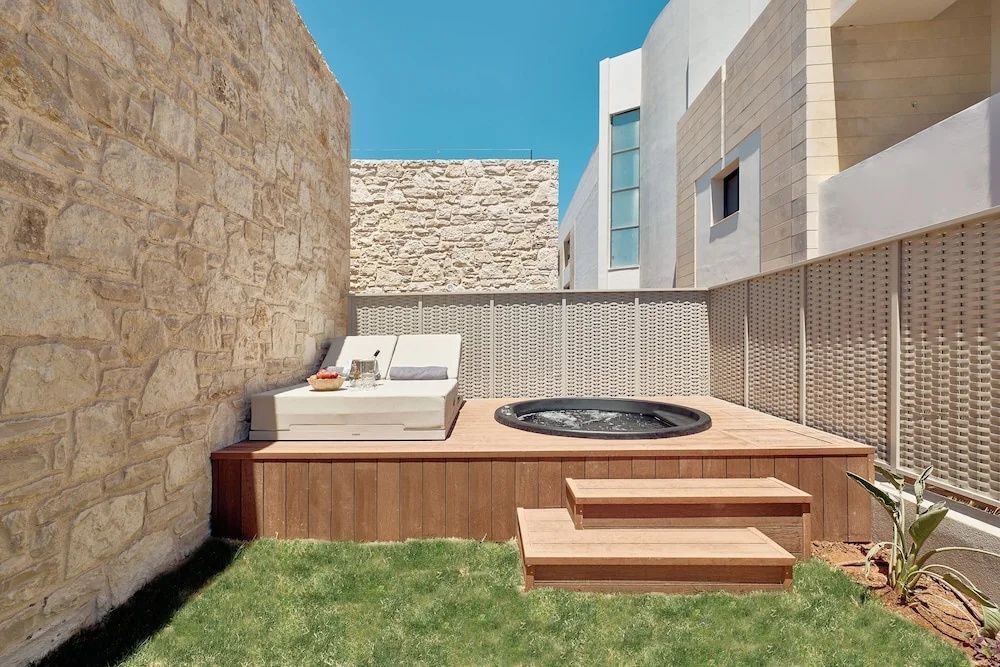 Holzterrasse mit Treppenzugang, einem eingelassenen Whirlpool und einer Liegemöglichkeit.