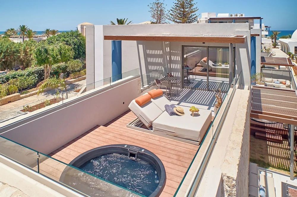 Blick von oben auf eine private Terrasse mit rundem Whirlpool und Liegebett.