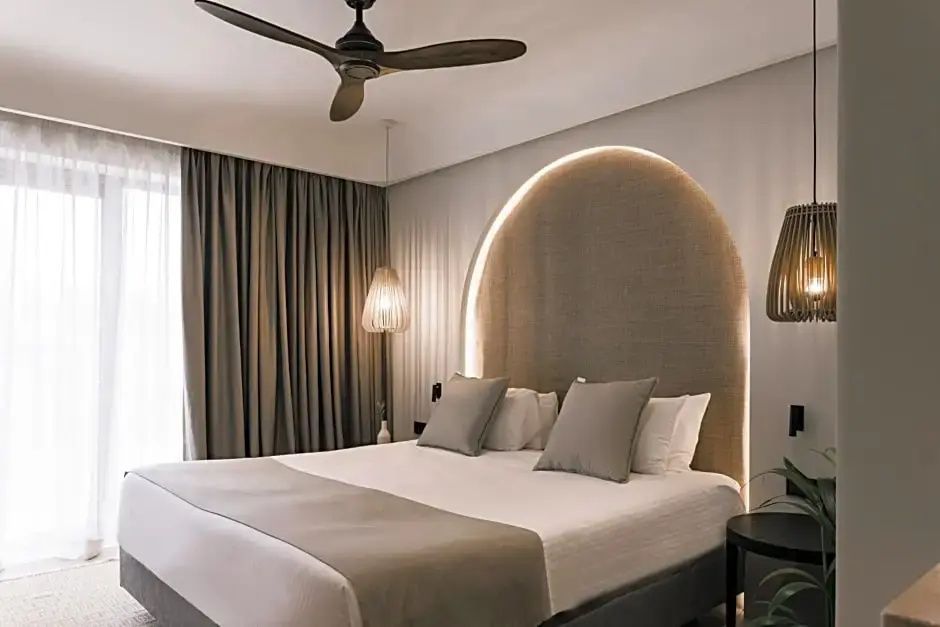 Großes Doppelbett mit beleuchteter Wandnische, Kissen und Deckenventilator.