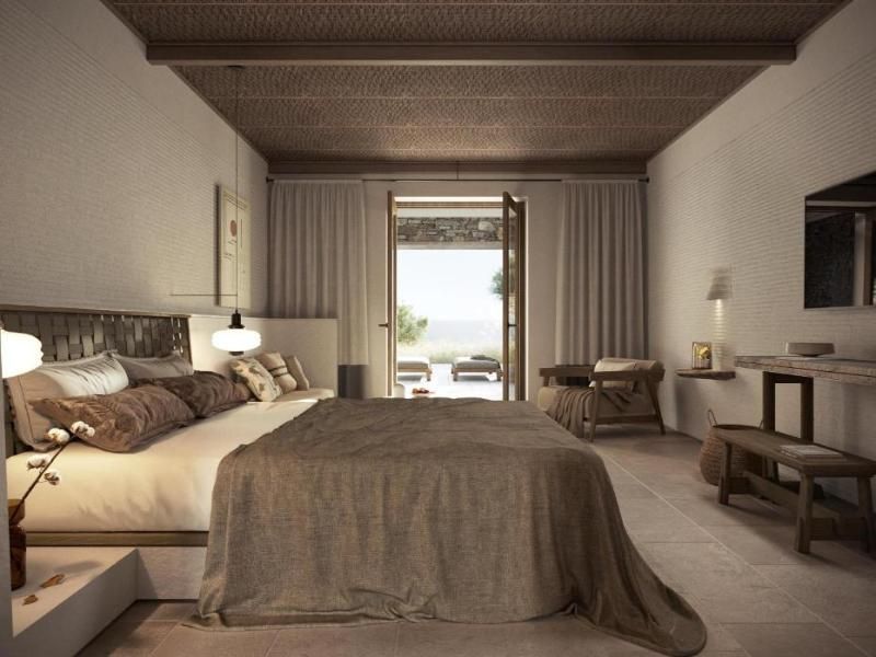 Hell eingerichtetes Hotelzimmer mit großem Doppelbett, Deckenbalken und Blick auf die Terrasse.