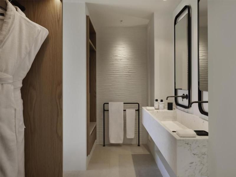 Badezimmer mit langem Waschtisch aus Marmor, schwarzer Armatur und Handtuchhalter.