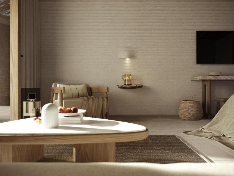 Heller Wohnbereich einer Suite mit niedrigem Holztisch und bequemem Sessel.