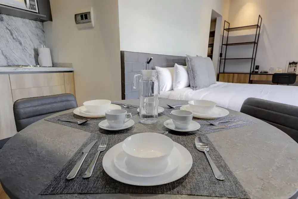 Gedeckter Esstisch mit weißem Geschirr und einer Karaffe im Zimmer.