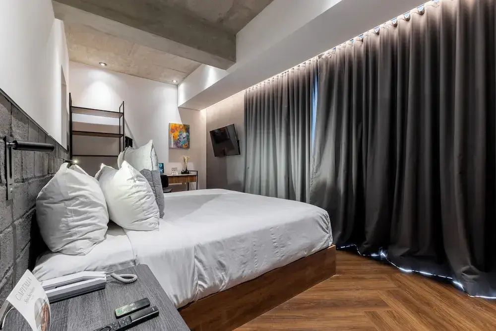 Schlafbereich mit einem Doppelbett und dunklen Vorhängen am Fenster.