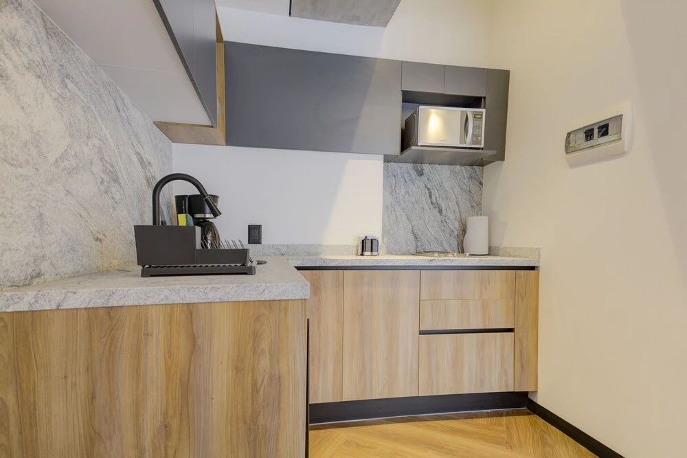 Küchenzeile aus Holz und grauem Element mit Mikrowelle und Spüle.