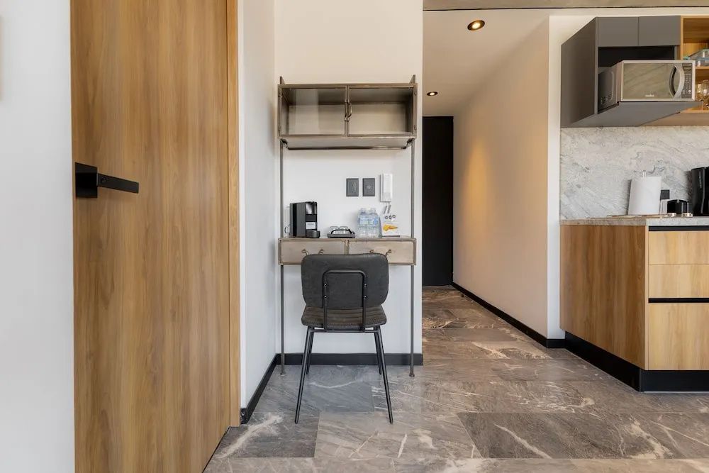 Kleine Arbeitsecke mit Schreibtisch, Stuhl und Kaffeemaschine im Apartment.