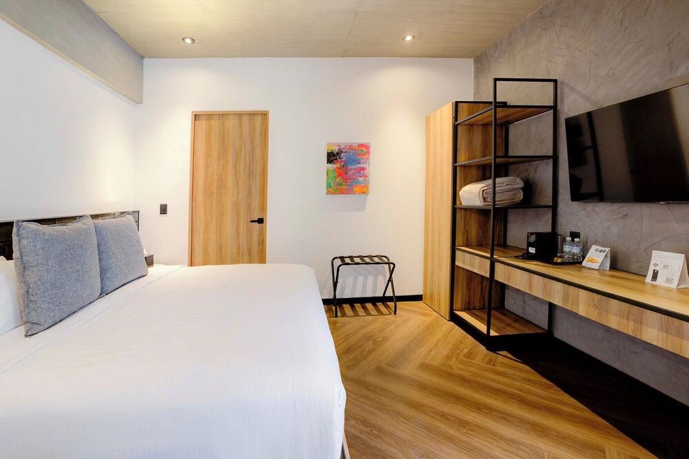 Hell eingerichtetes Schlafzimmer mit Doppelbett, Holzfußboden und offenem Kleiderschrank.