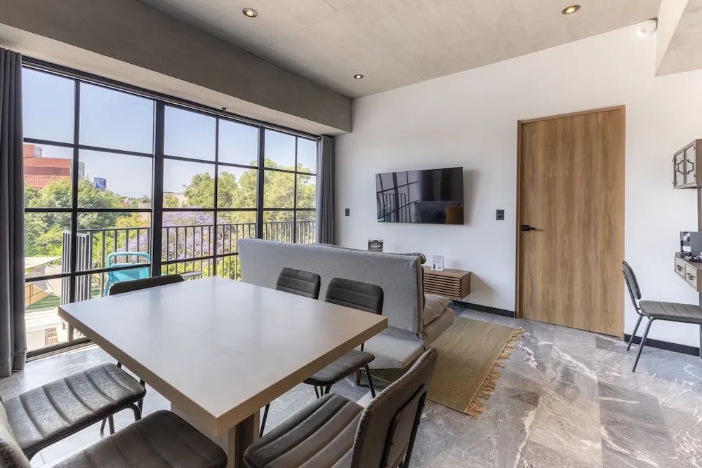 Modernes Wohnzimmer mit Esstisch, Sofa, Fernseher an der Wand und großem Fenster.