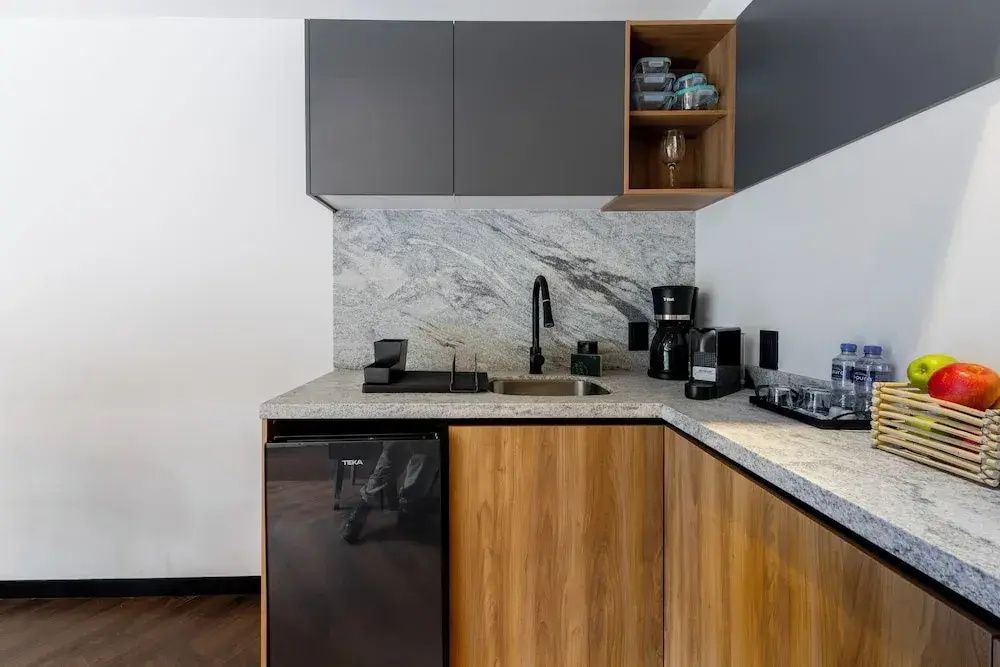 Moderne Küchenzeile im Apartment mit Spülbecken, Kaffeemaschine und Kühlschrank.