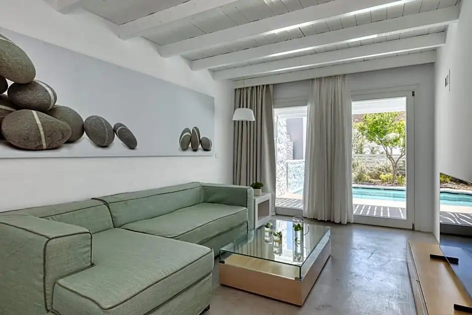 Wohnbereich einer Suite mit grüner Sitzecke, Glascouchtisch und Balkontüren zum Pool.