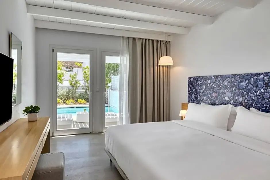 Helles Schlafzimmer mit großem Doppelbett und Glastür zum privaten Außenpool.
