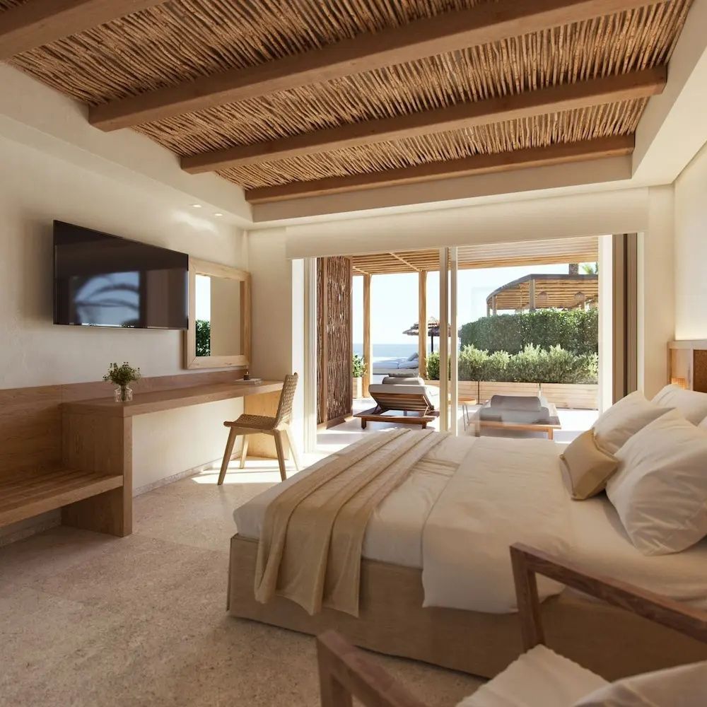 Helles Hotelzimmer mit Holzdecke, großem Doppelbett, Schreibtisch und Zugang zur Terrasse.