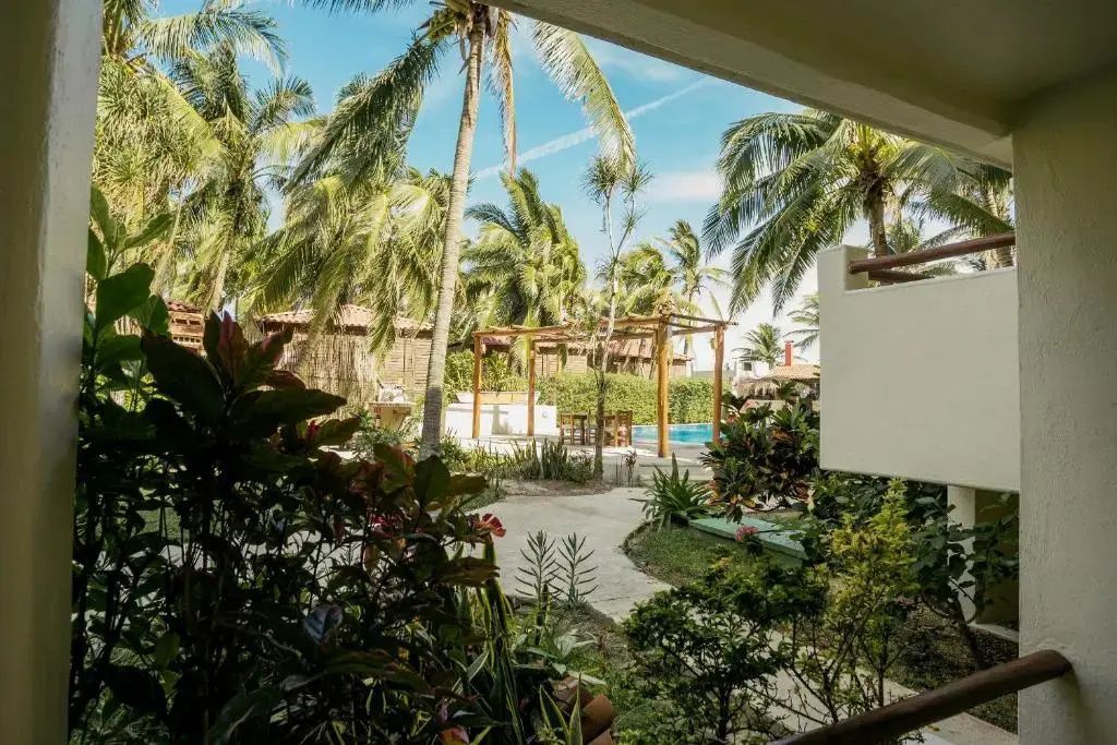 Ausblick von einem Balkon auf eine grüne Gartenanlage mit hohen Palmen.