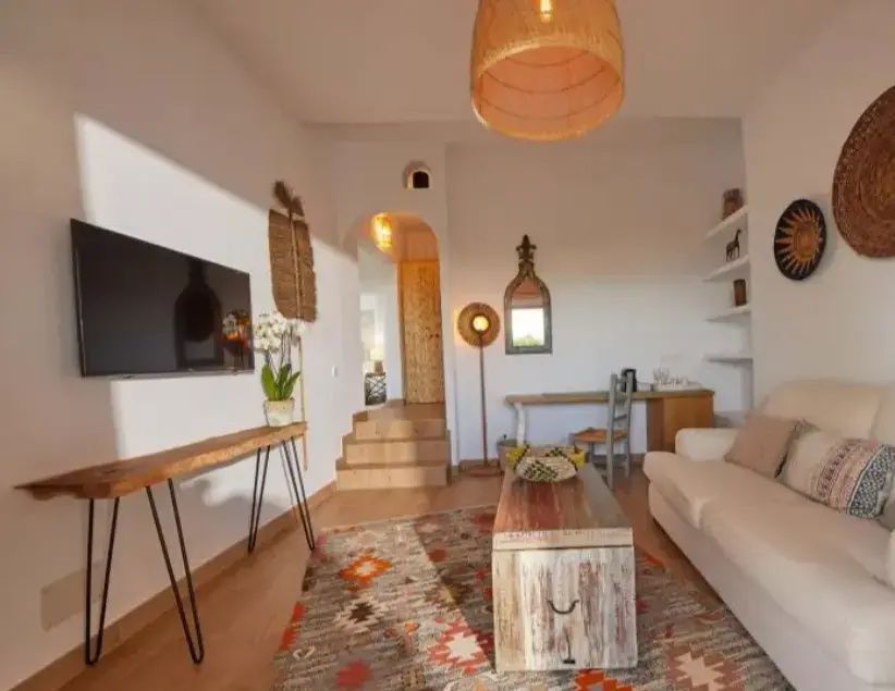 Wohnbereich eines Hotelzimmers mit Sofa, Holztisch, TV Gerät und Stufen zu einem weiteren Raum.